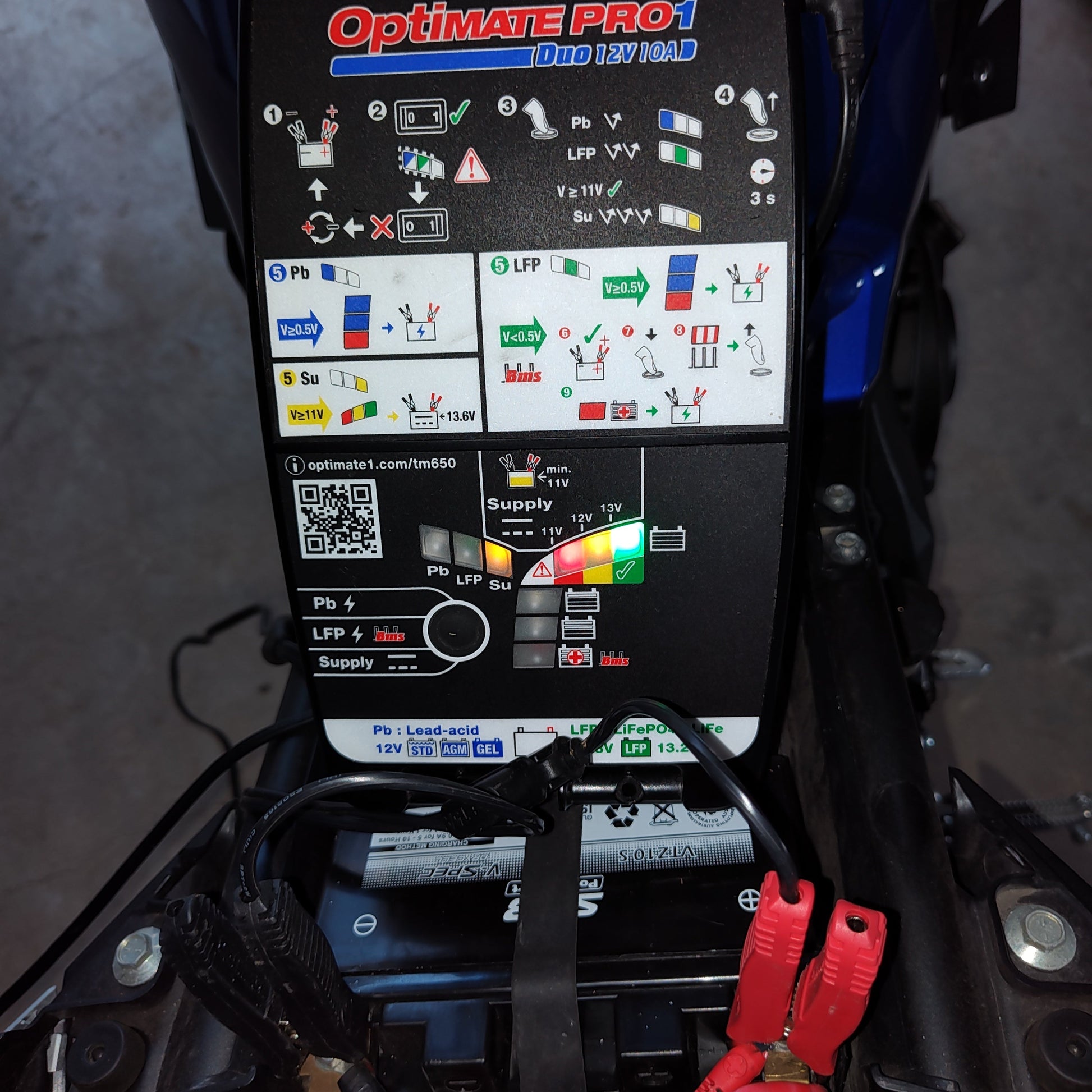 Optimate Pro1 battery charger on a motorcycle with visible connections.